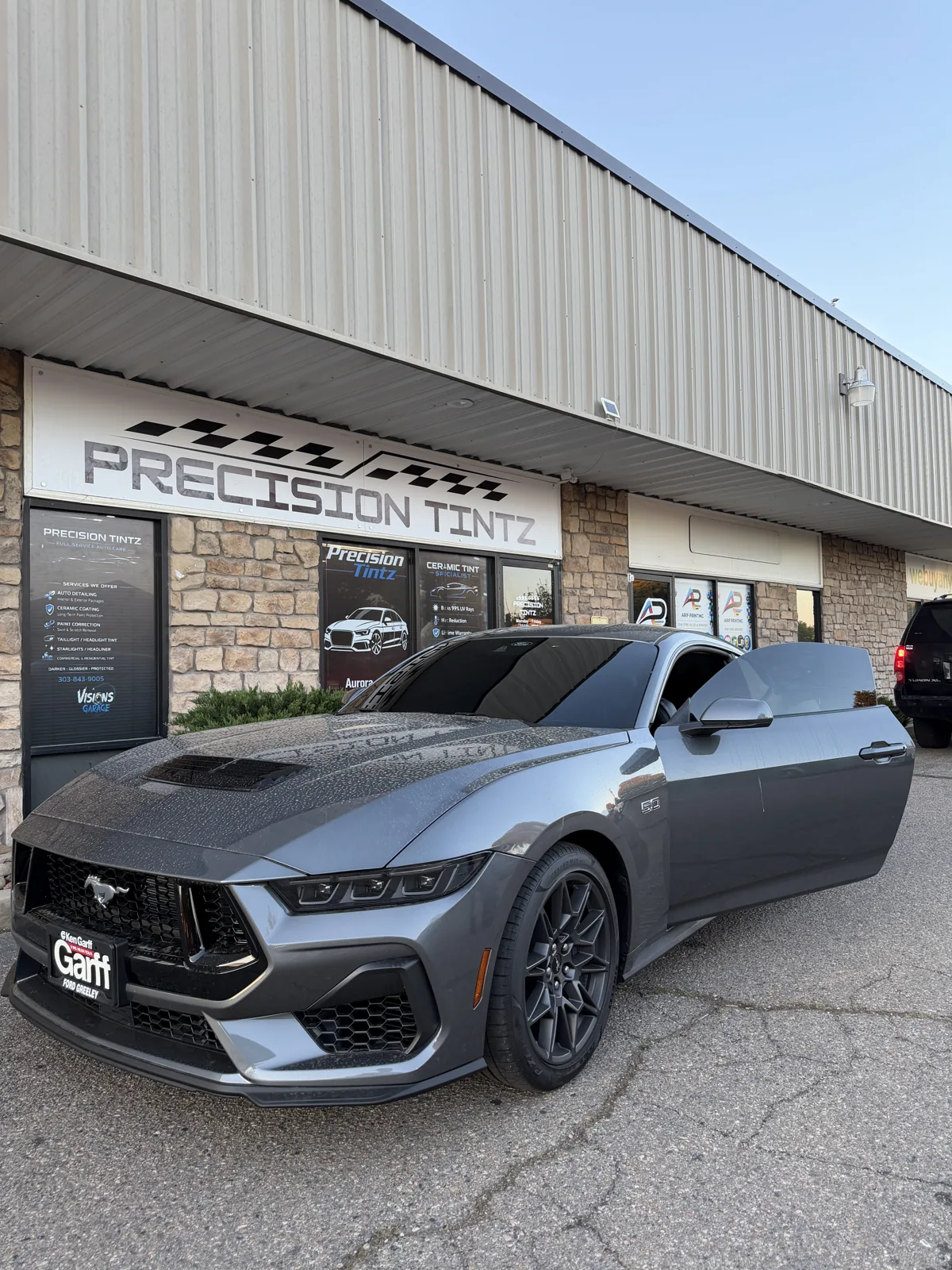 Grey Ford Mustang GT with freshly installed ceramic window tint parked outside the Precision Tintz shop on Chambers Road in Aurora, Colorado