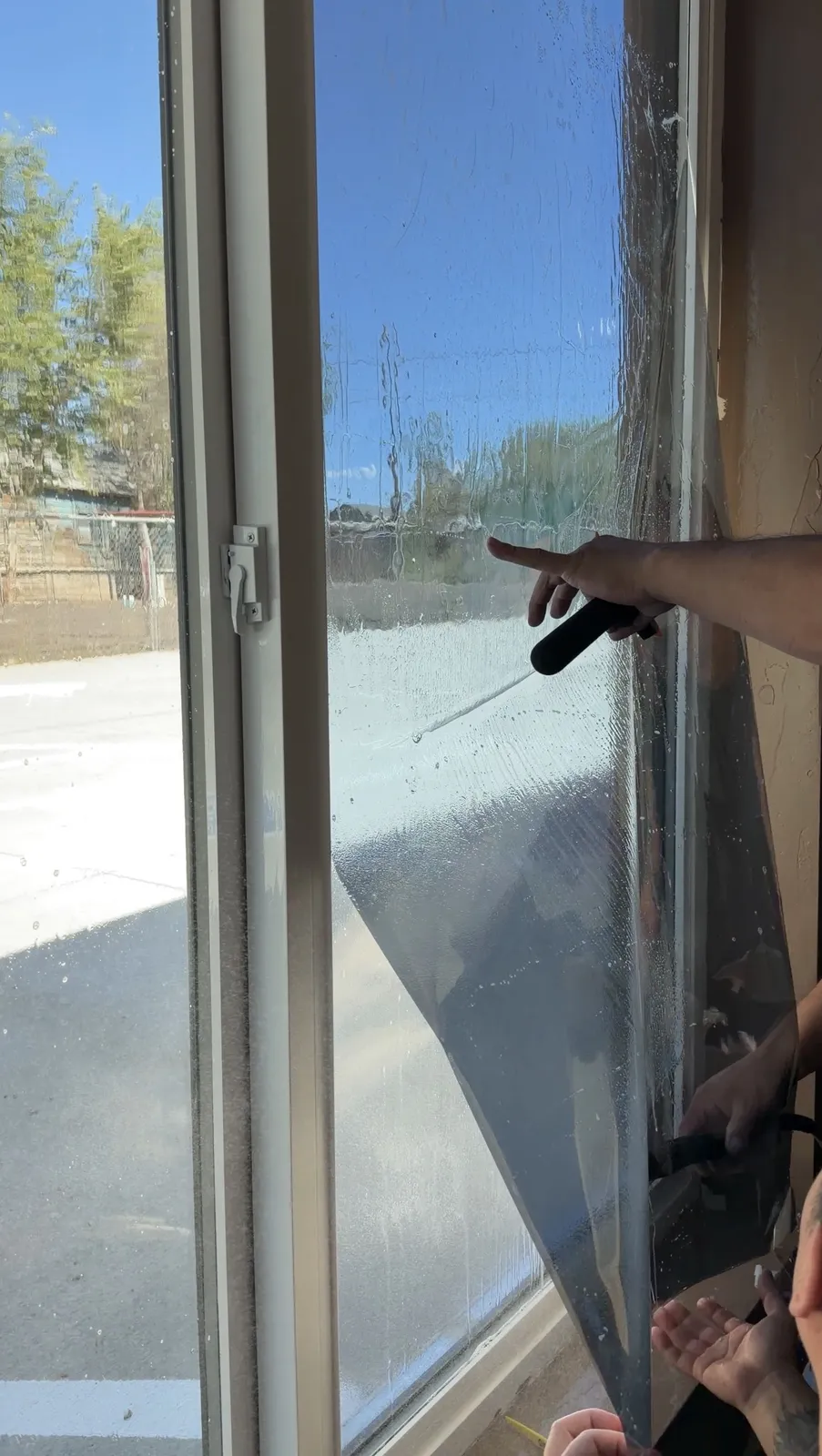 Close-up of window film being squeegeed onto glass during an install