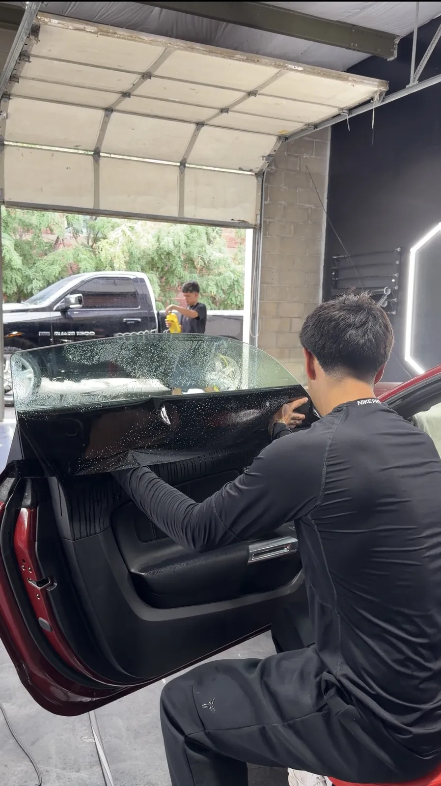 Technician laying window tint film on a car door glass at Precision Tintz in Aurora