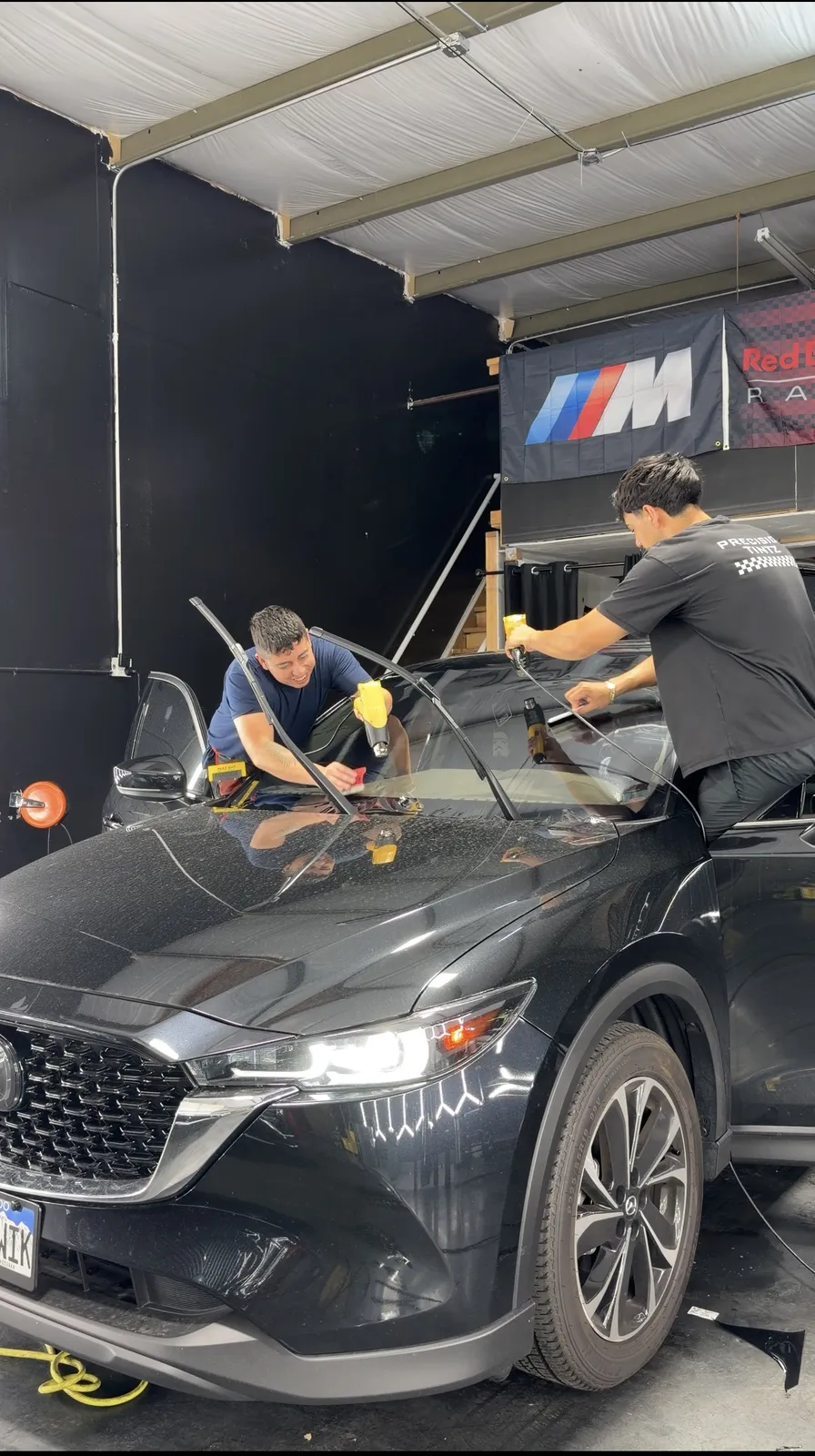 Two Precision Tintz installers laying ceramic film across a windshield